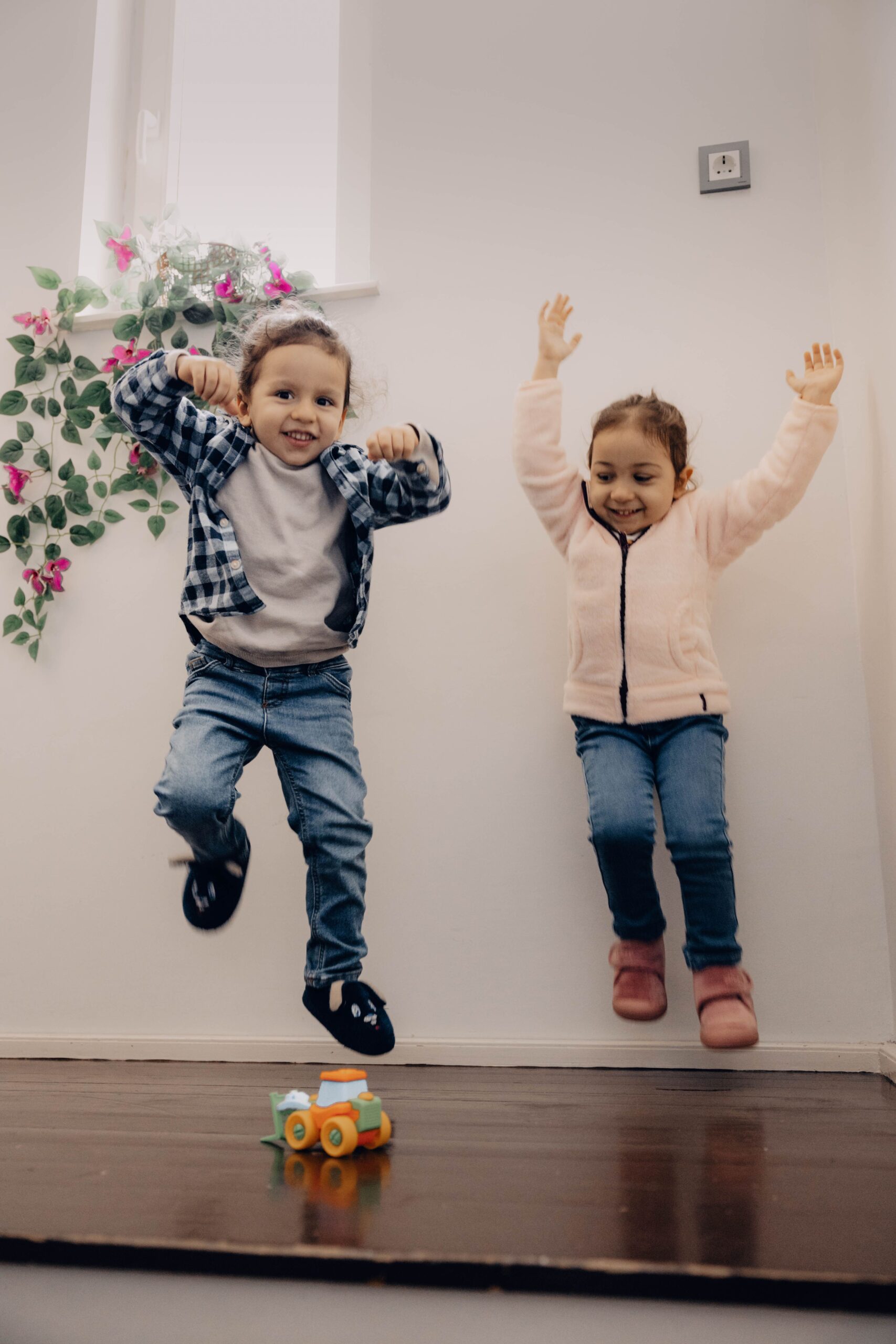 Two children joyfully jumping indoors, capturing the essence of playful childhood excitement.