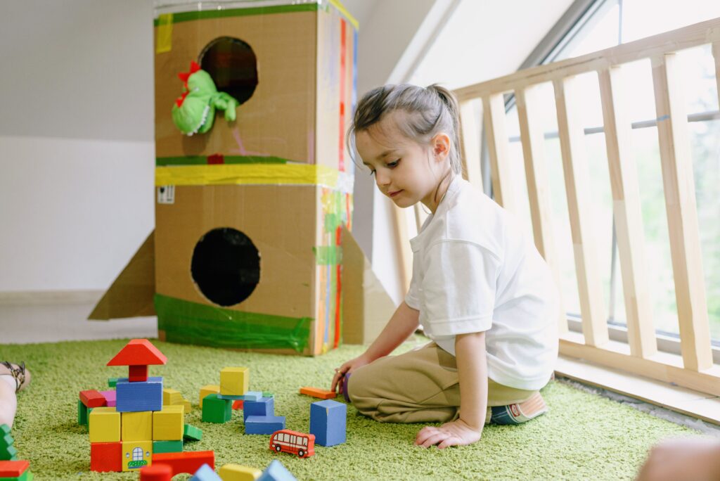 Young girl playing with colorful blocks in a bright indoor playroom.